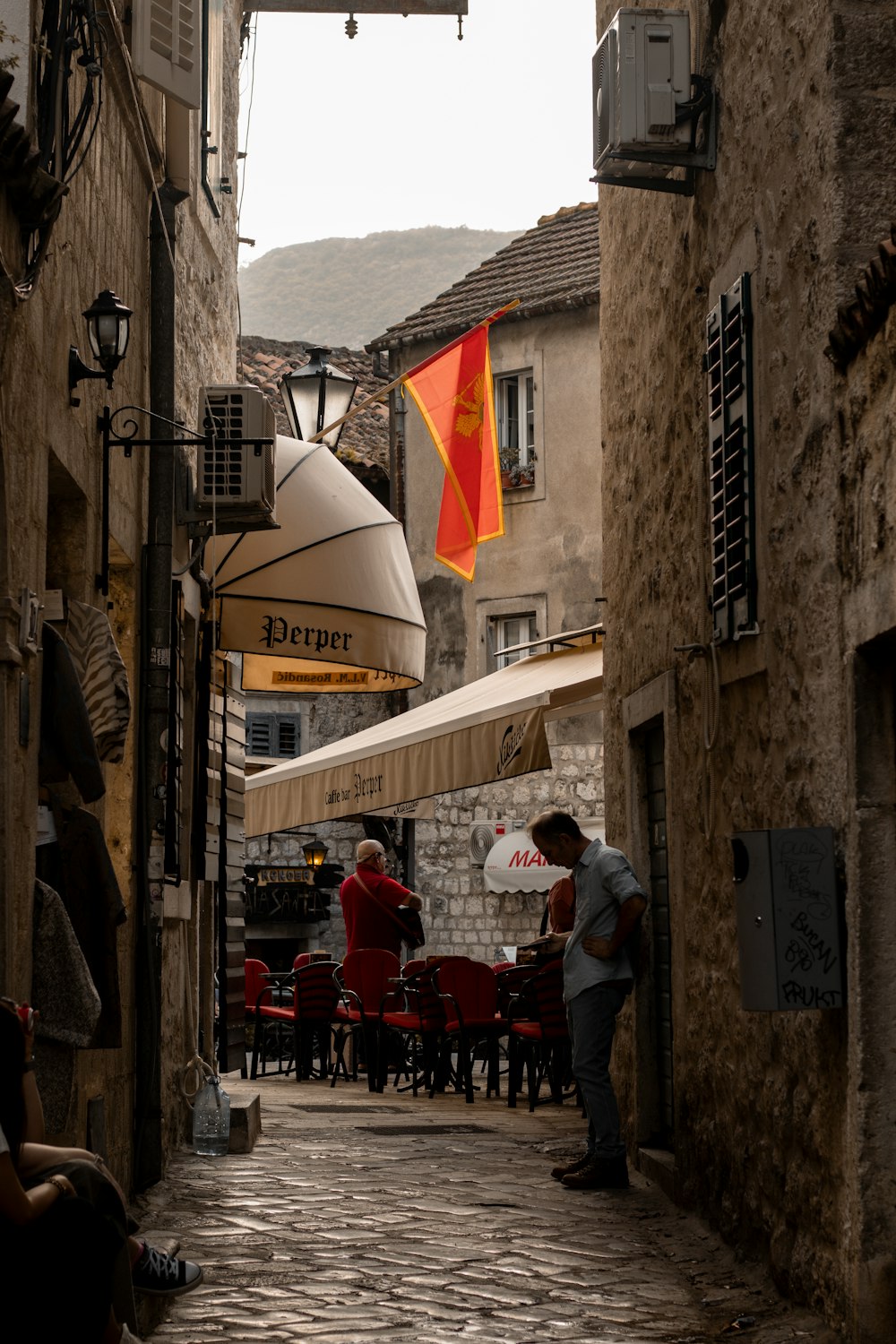 a cobblestone street lined with tables and umbrellas