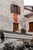 a stone building with a red flag hanging from it's side