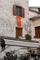 a stone building with a red flag hanging from it's side