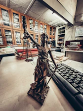 a statue of a lady justice holding a sword next to a keyboard