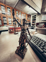 a statue of a lady justice holding a sword next to a keyboard