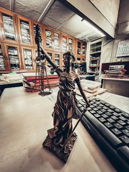 a statue of a lady justice holding a sword next to a keyboard