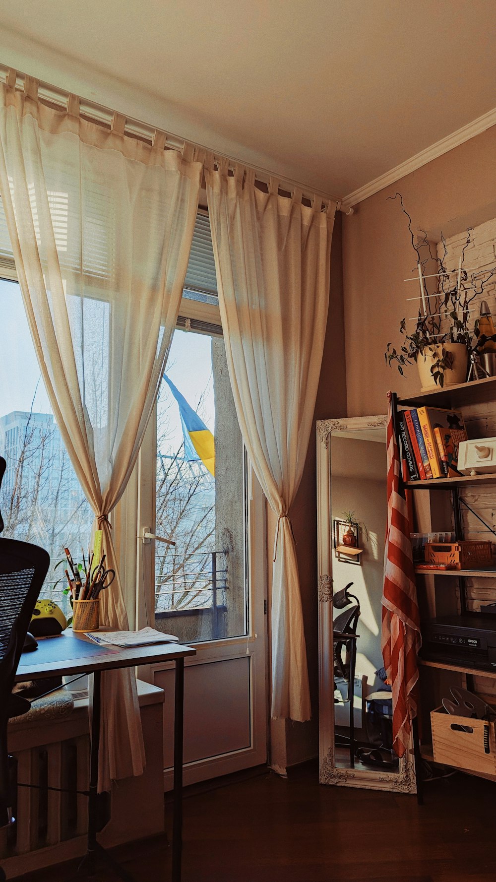 a room with a desk, bookshelf and a window