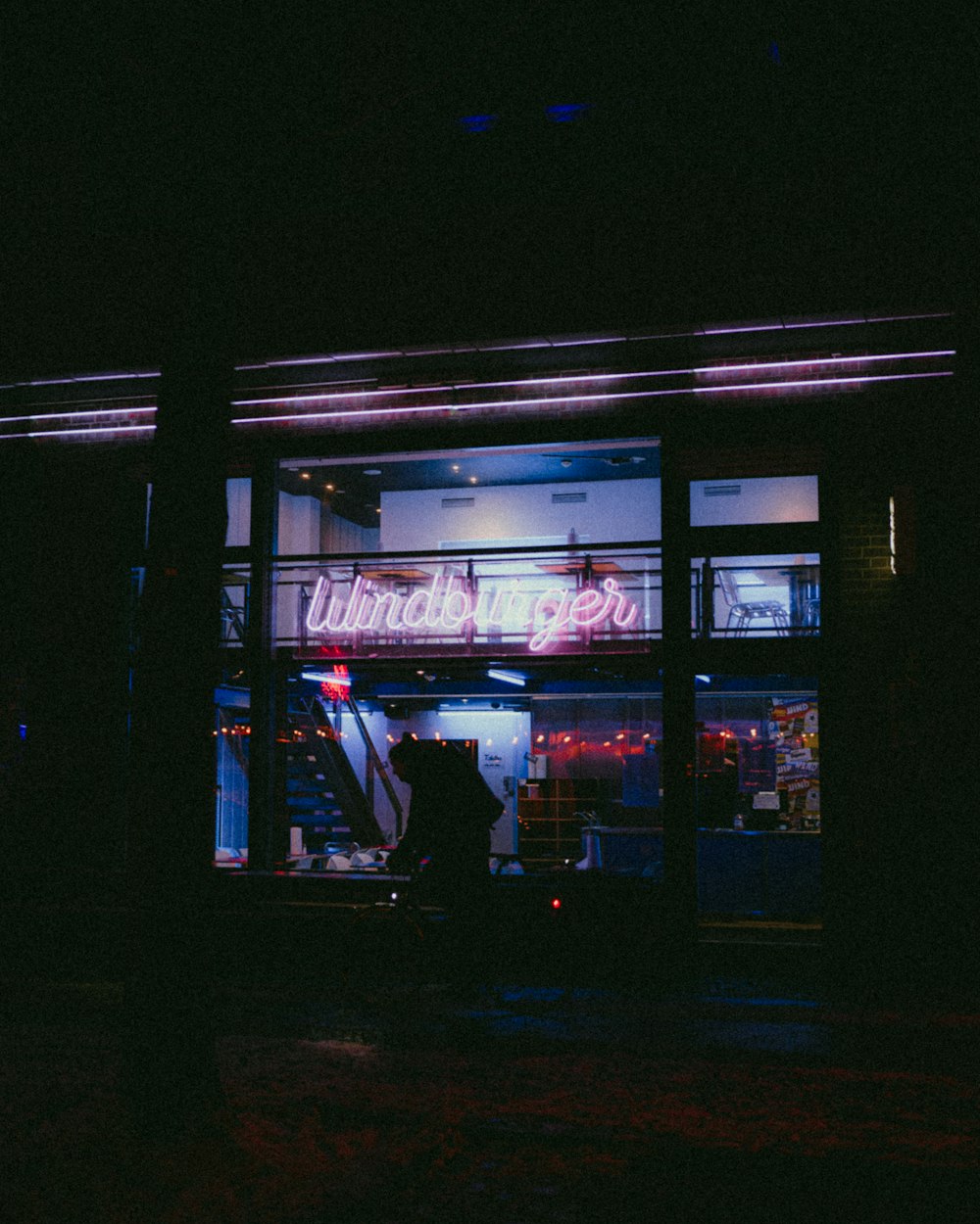 a store front at night with a neon sign in the window