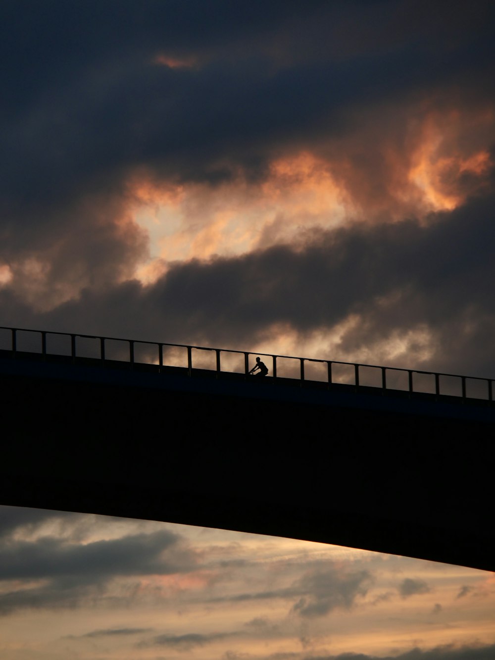a person walking across a bridge at sunset