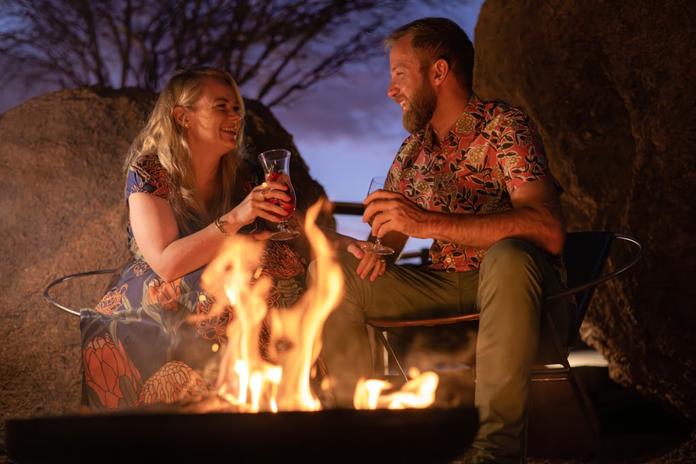 a man and a woman sitting next to a fire
