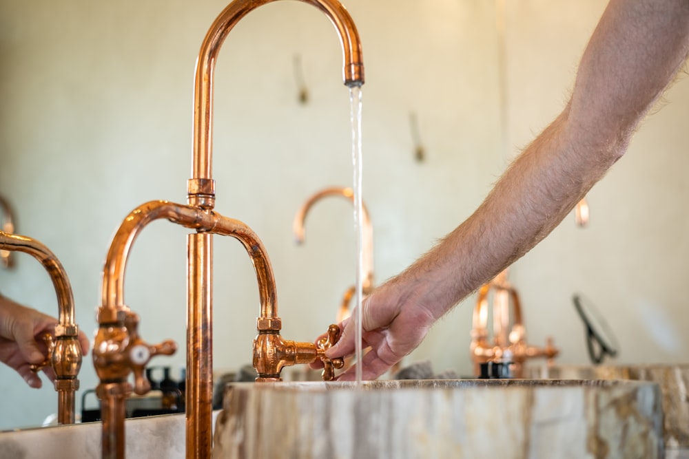 a man is washing his hands in a copper faucet