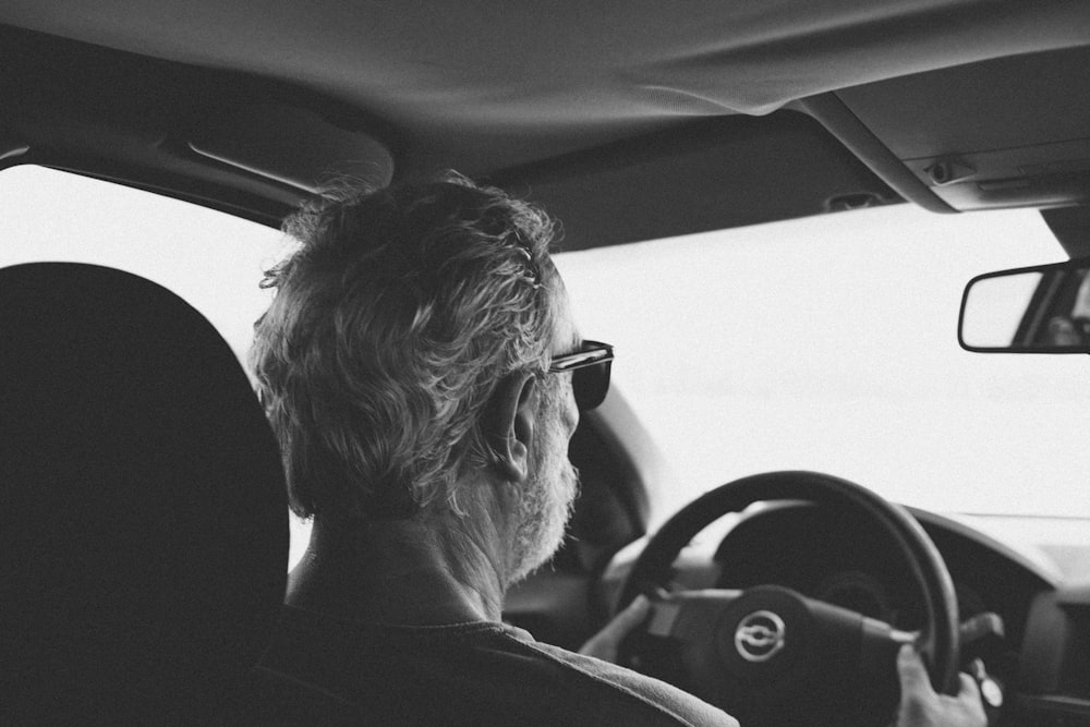 a man driving a car with a steering wheel