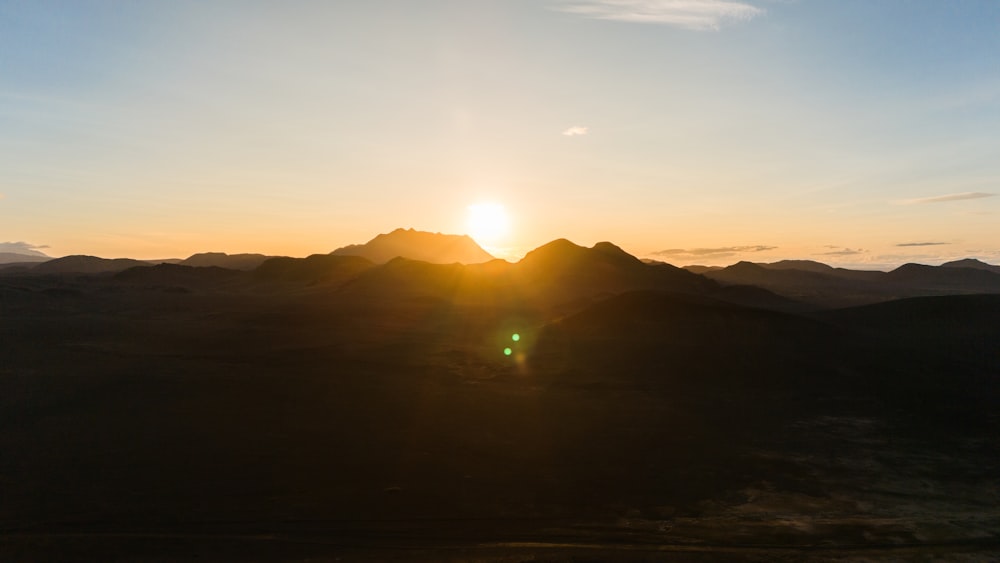 the sun is setting over a mountain range