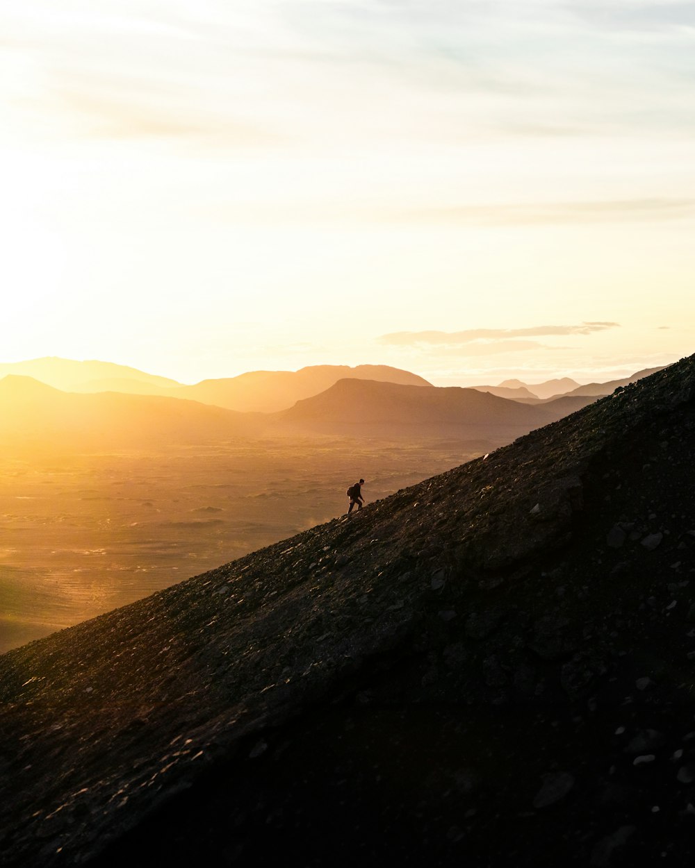 eine Person, die bei Sonnenuntergang einen Hügel hinaufgeht