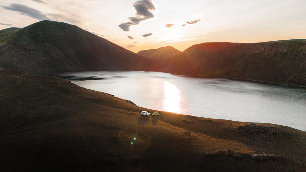 the sun is setting over a lake in the mountains