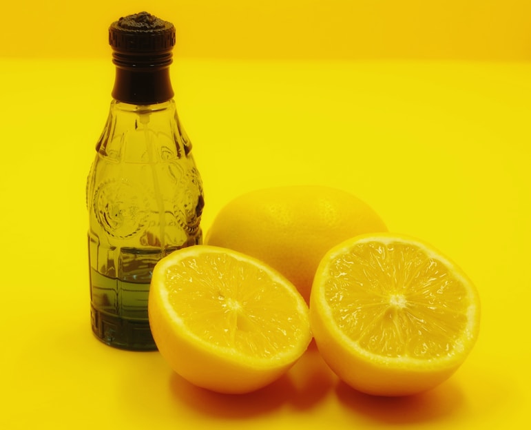 a bottle of water and two lemons on a yellow background