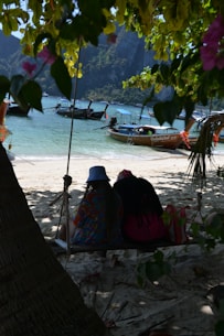 two people sitting in a hammock on the beach