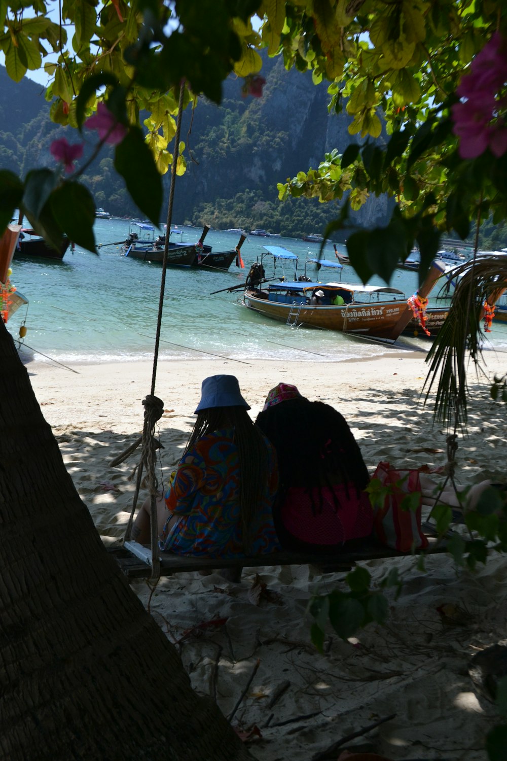 two people sitting in a hammock on the beach