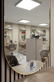 a mirror reflecting a hair salon with chairs