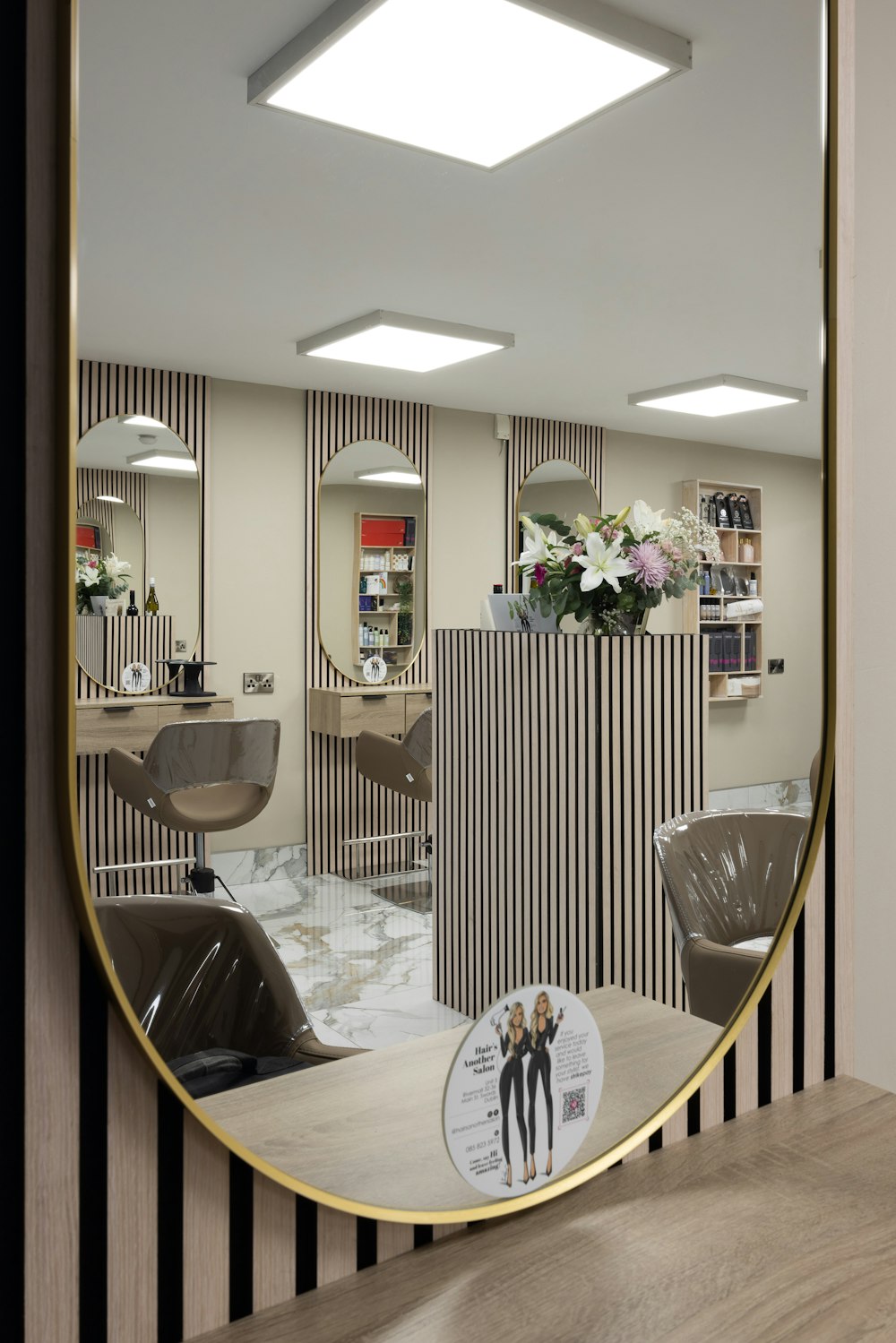 a mirror reflecting a hair salon with chairs