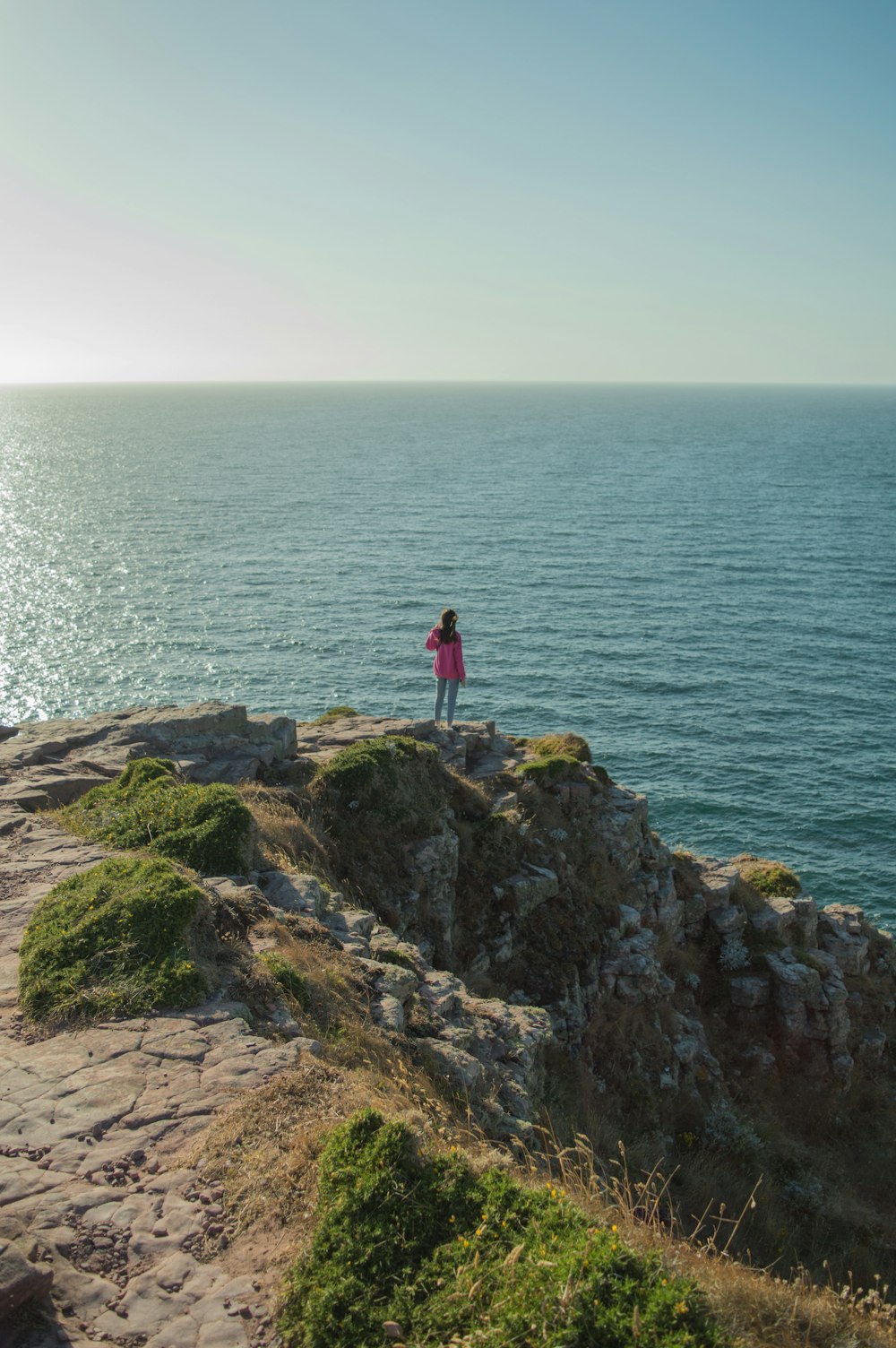 una persona in piedi su una scogliera che si affaccia sull'oceano