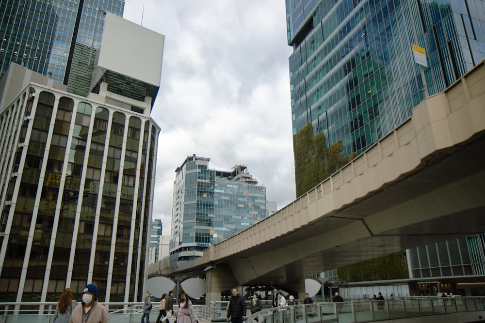 a group of people walking across a bridge next to tall buildings