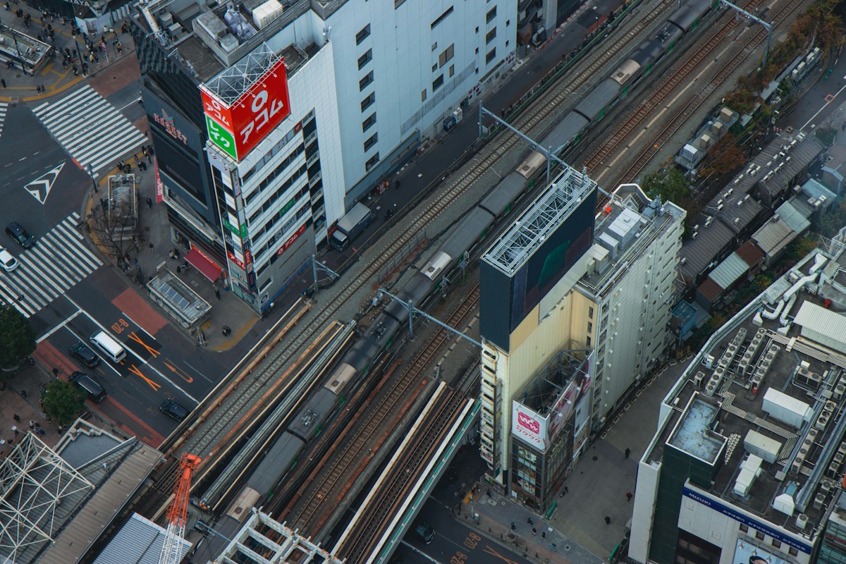 線路沿いに中低層の建物が密集する都市の街並みを上から見た写真