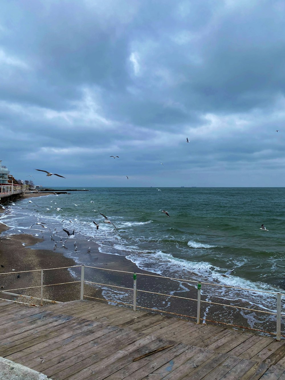 a pier with birds flying over the water