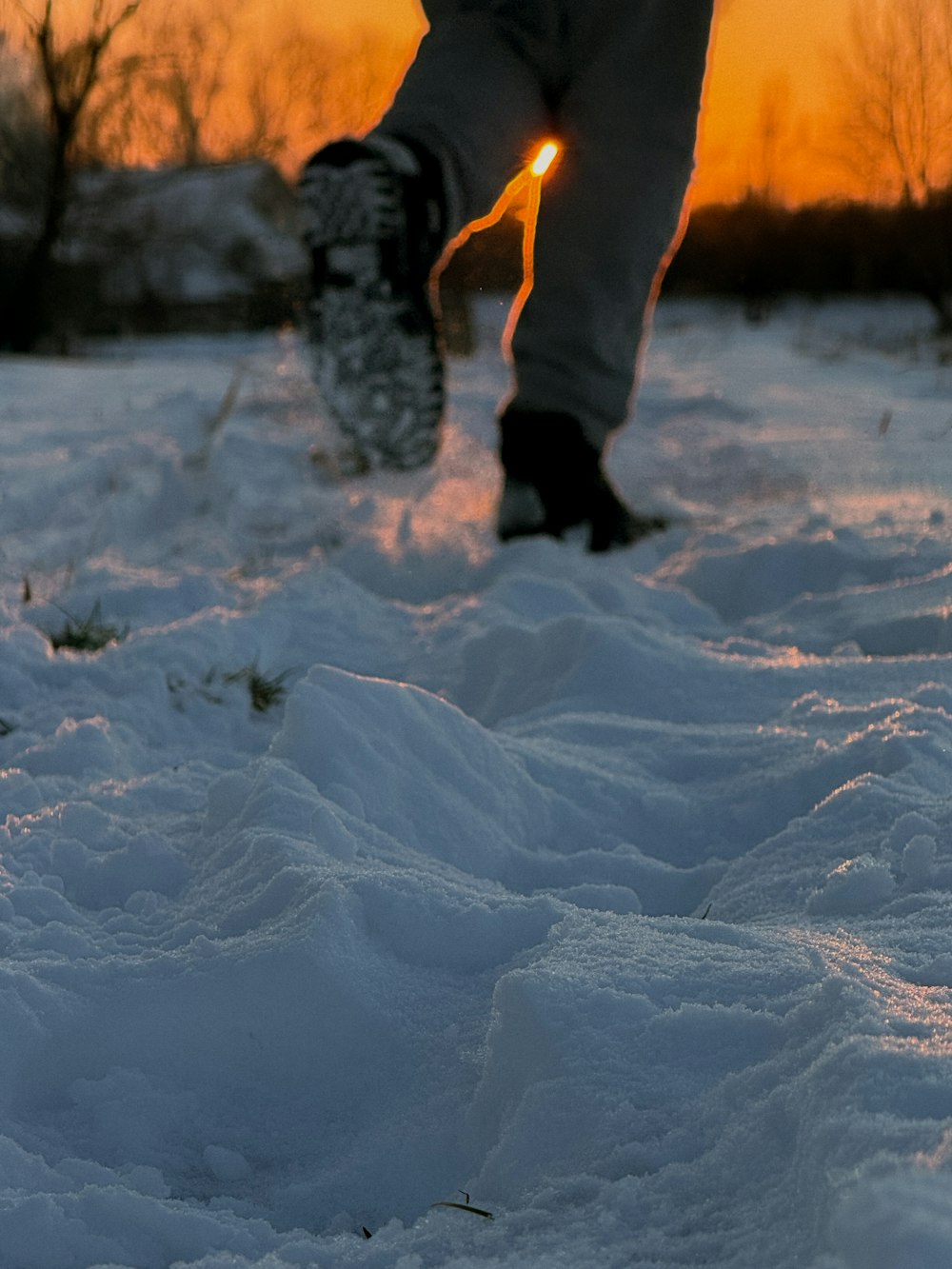 a person walking in the snow at sunset