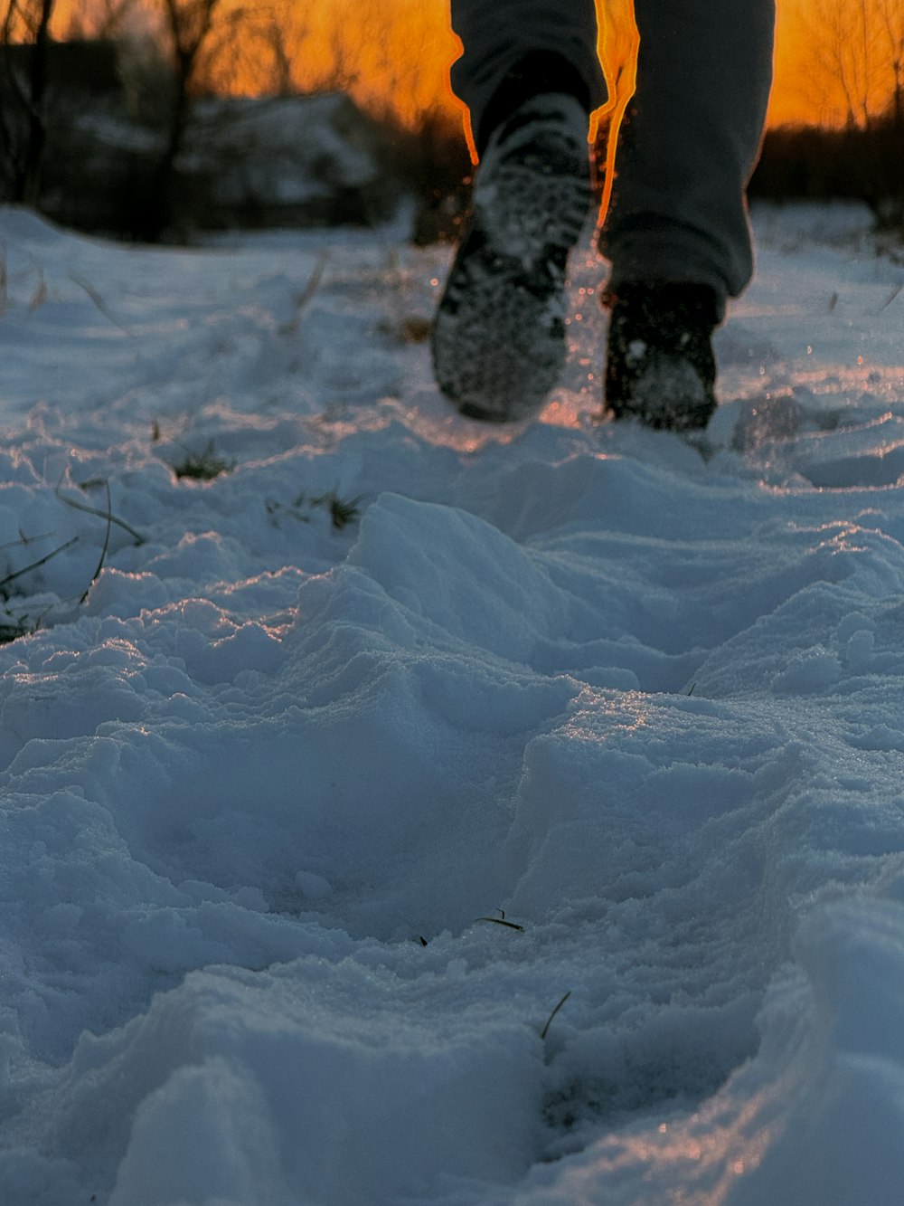 a person walking in the snow at sunset
