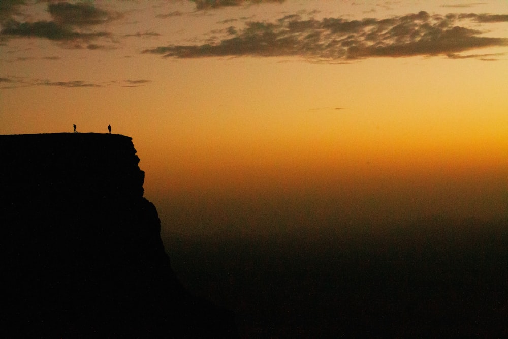 a couple of people standing on top of a cliff