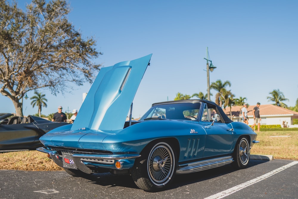 a blue car with its hood open in a parking lot