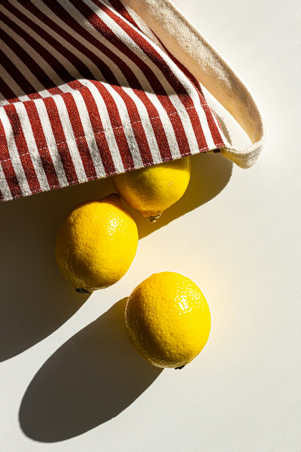 tre limoni in un sacchetto a righe bianche e rosse