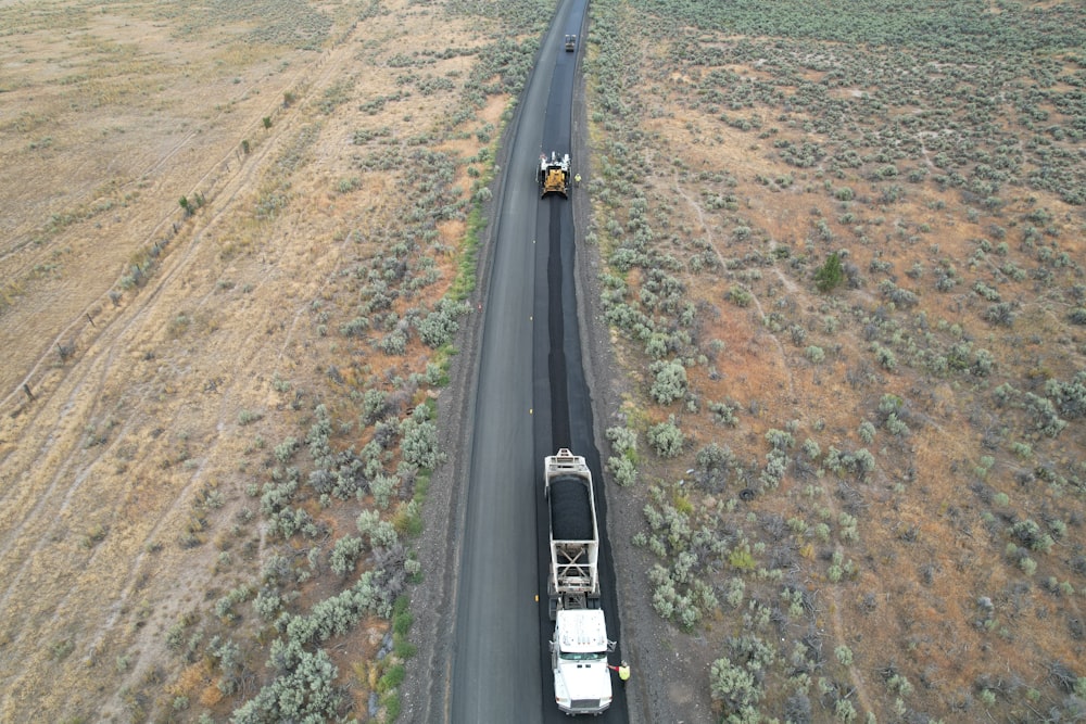 two trucks driving down a road in the middle of the desert