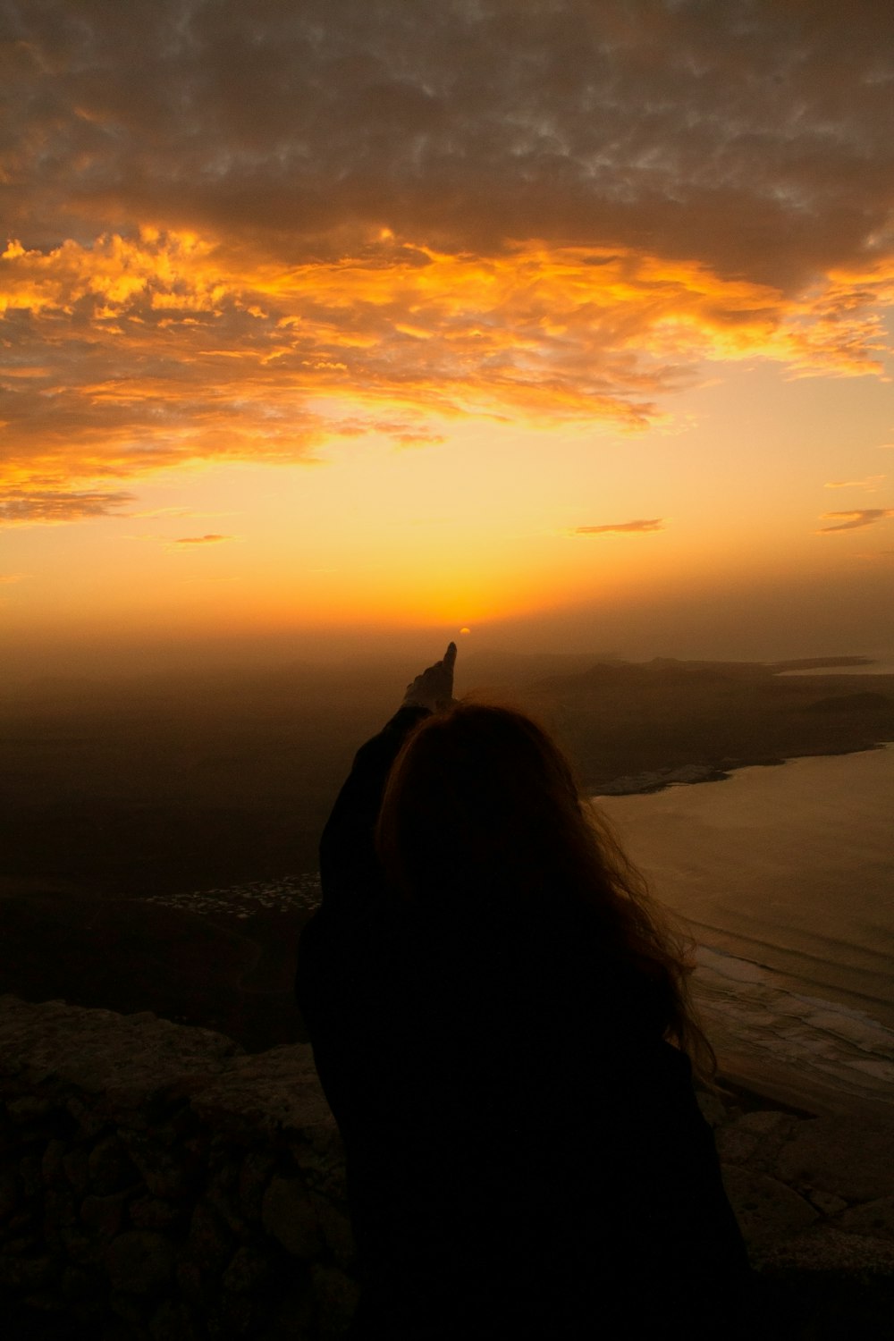 a woman standing on top of a mountain with a sunset in the background