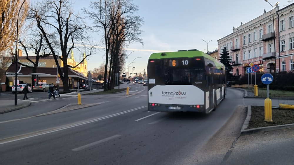 a green and white bus driving down a street