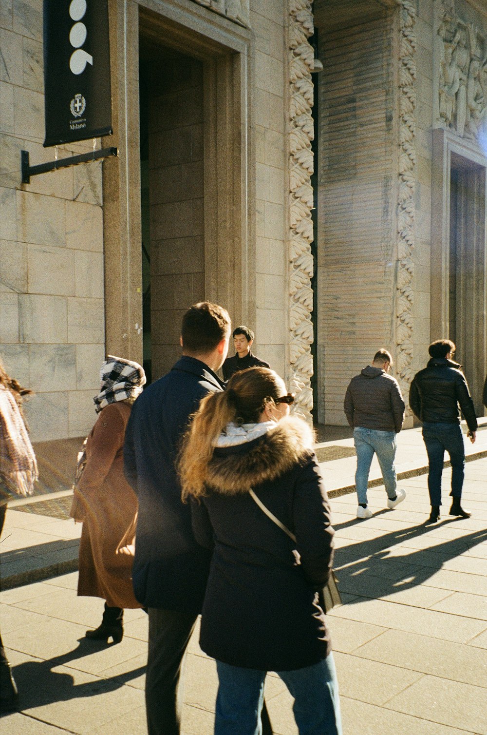 a group of people walking down a sidewalk next to a building