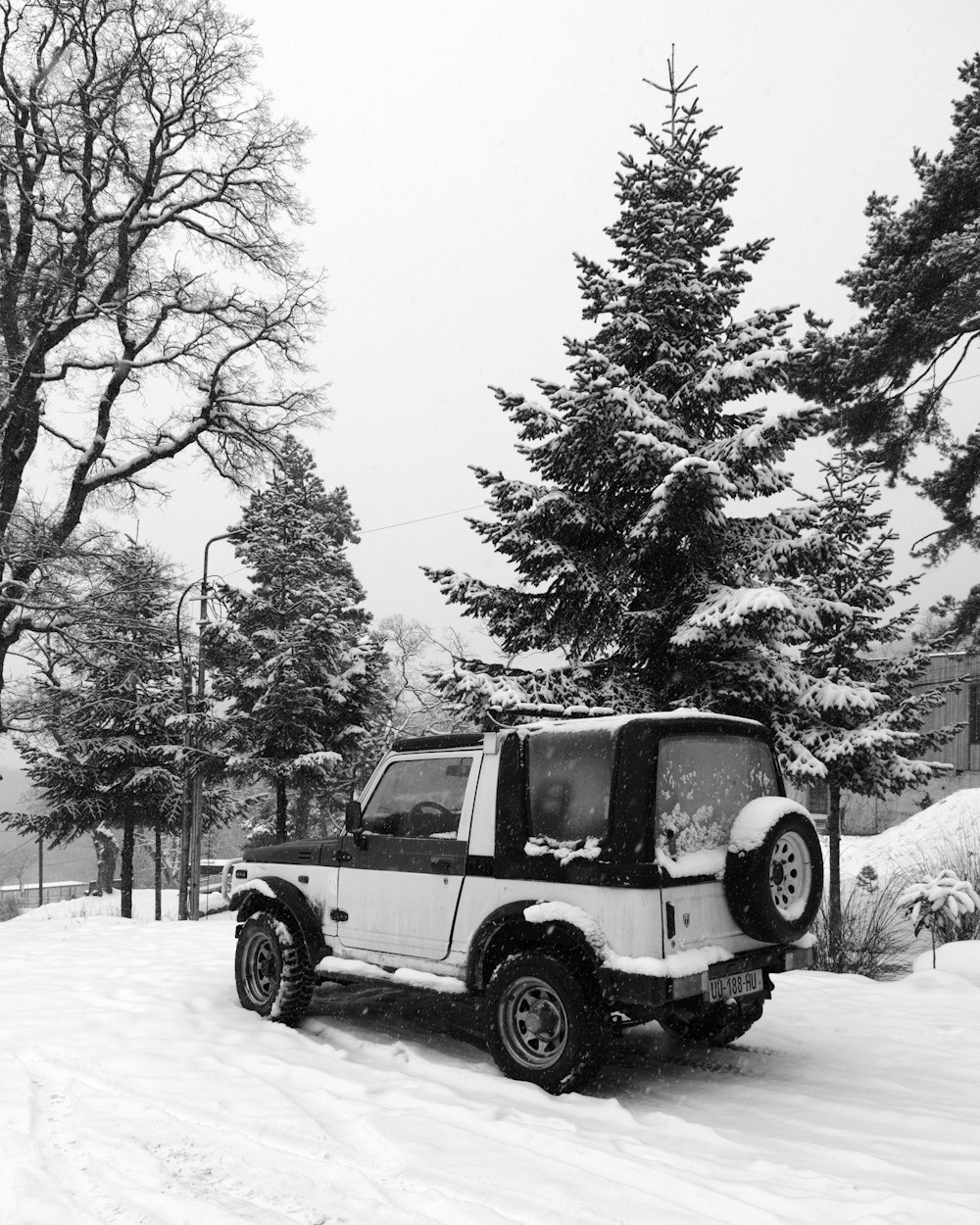 a black and white photo of a jeep in the snow
