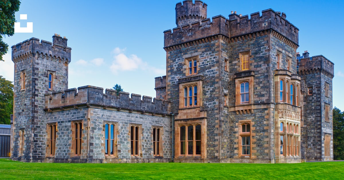 A large castle like building sitting on top of a lush green field photo ...