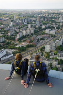 two people sitting on a ledge overlooking a city