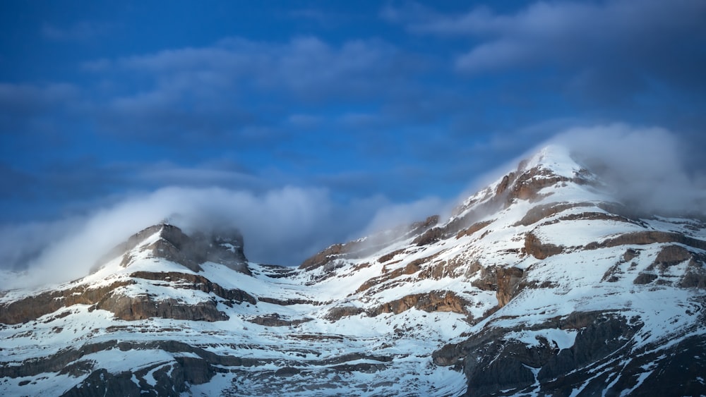 a mountain covered in snow under a cloudy sky