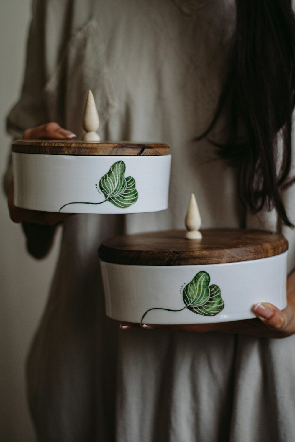 a woman holding two white dishes with green leaves on them