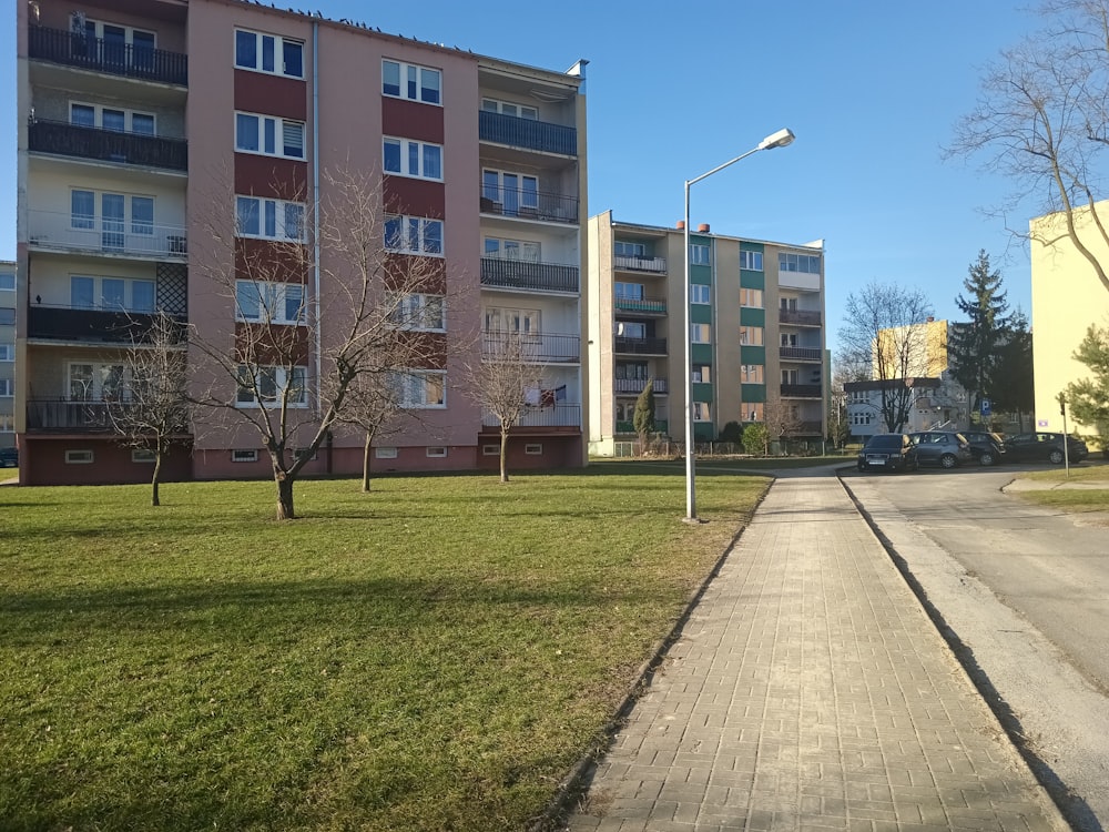 a grassy area next to a street with a building in the background