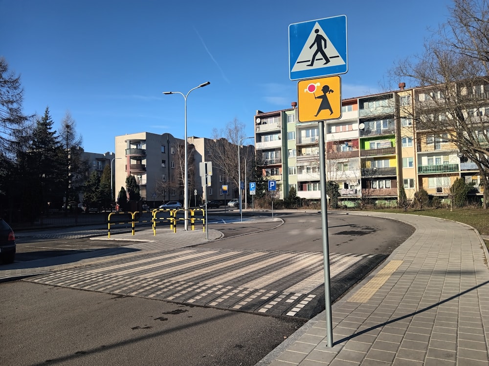 a blue and yellow pedestrian crossing sign sitting on the side of a road