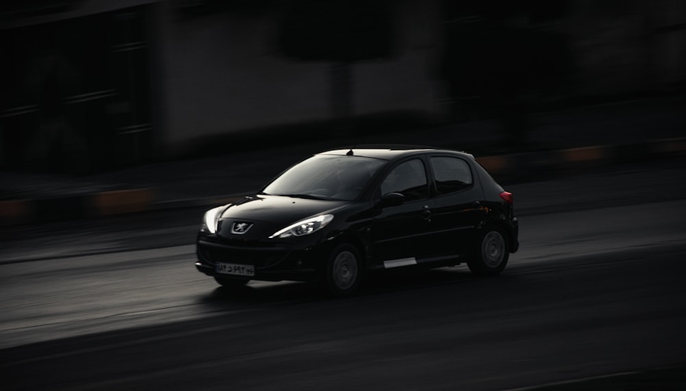 a small black car driving down a street