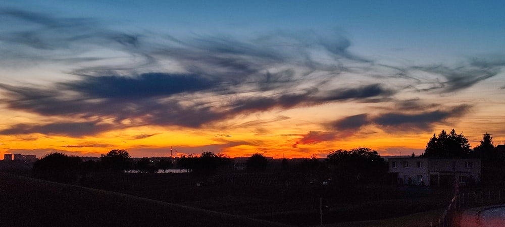 the sun is setting over a city with clouds in the sky