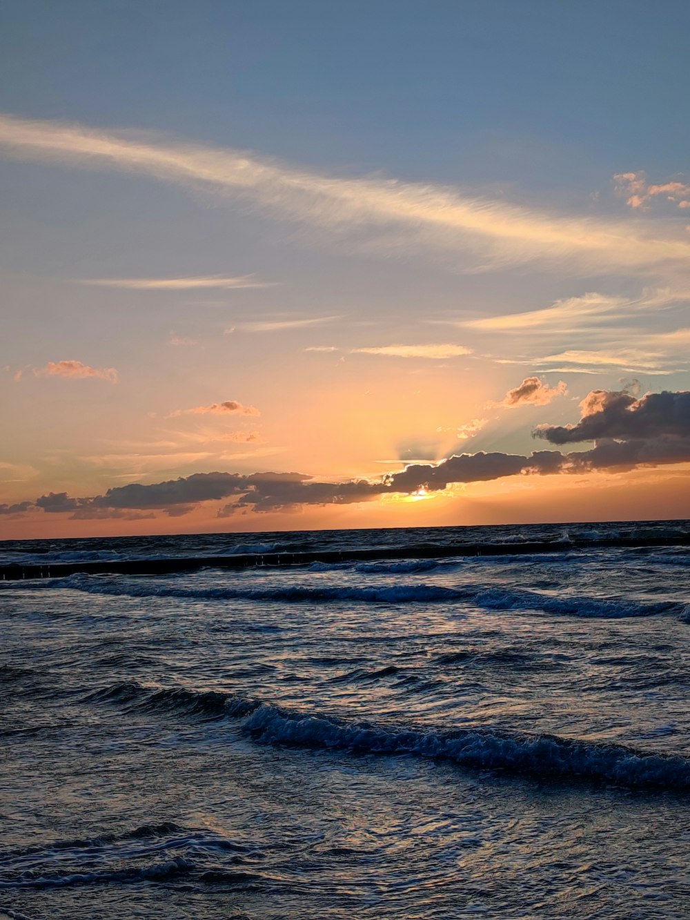 el sol se está poniendo sobre el océano con olas