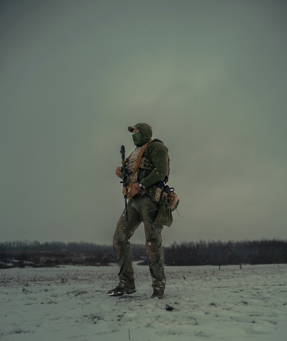 a man with a rifle standing in the snow