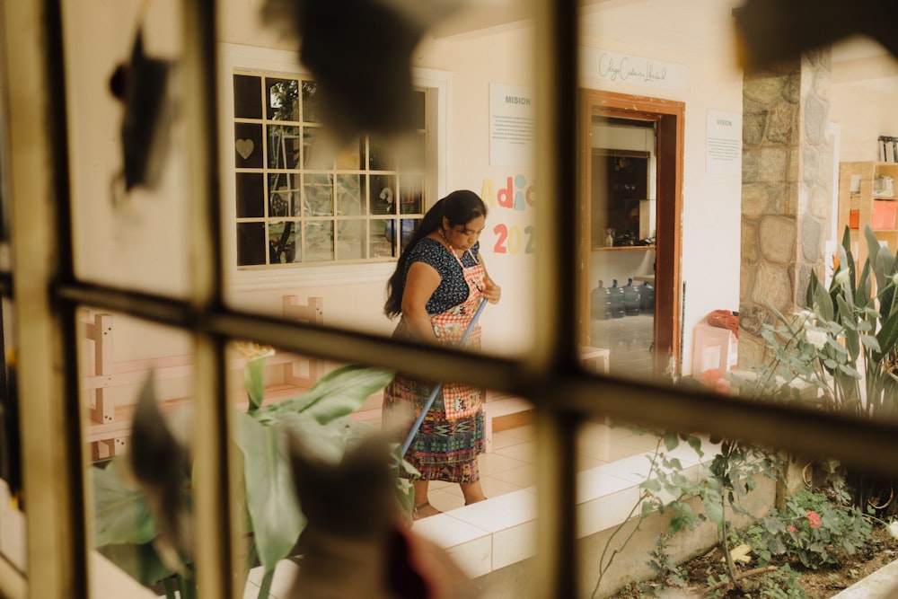 a woman standing in front of a window looking at her cell phone