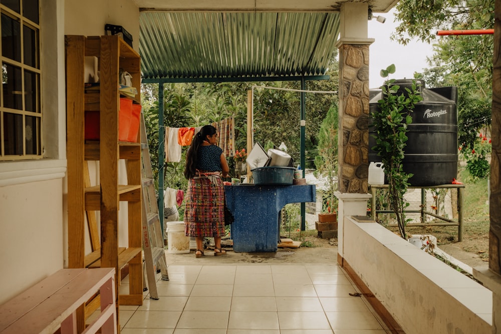 a woman standing in a kitchen next to a blue table