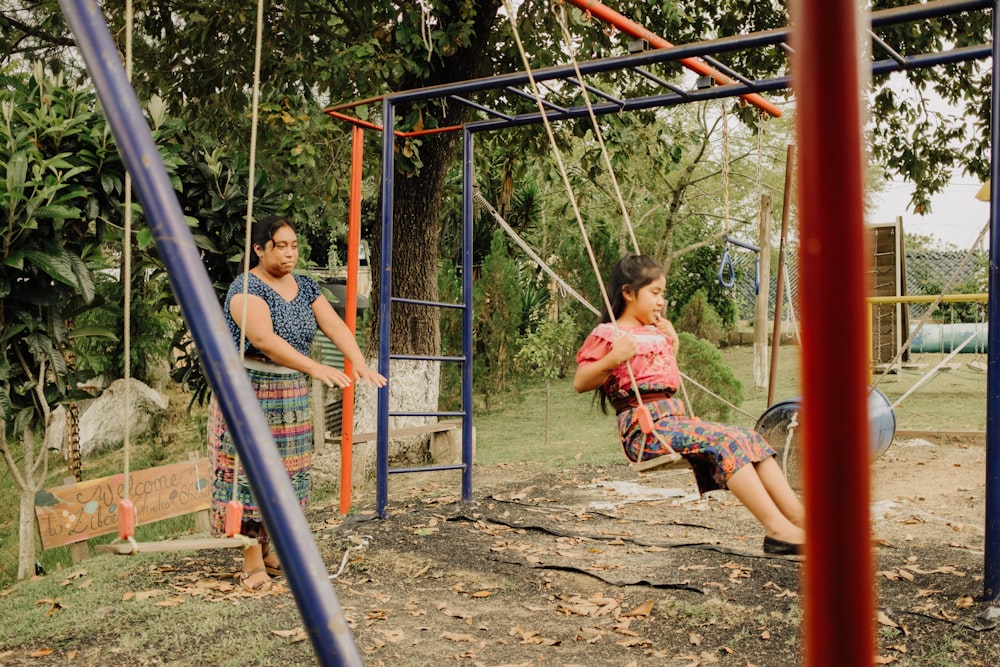 a man and a woman sitting on swings in a park