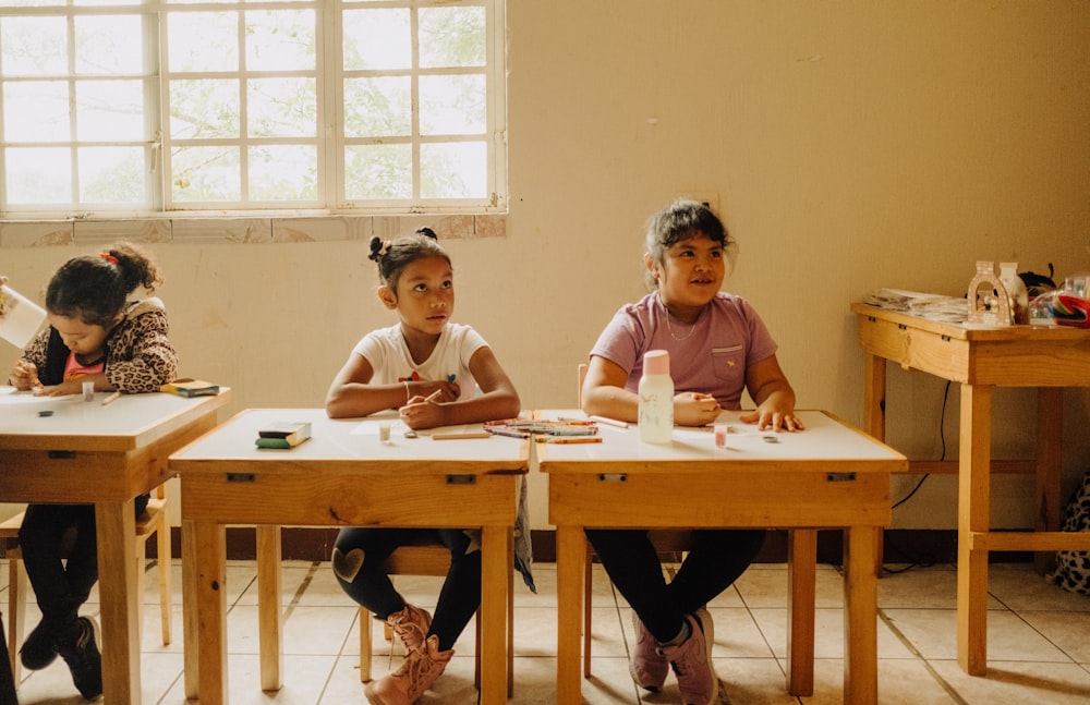 um grupo de crianças sentadas em mesas em uma sala