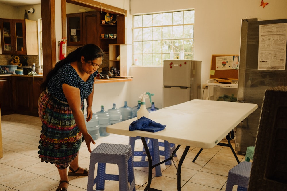 a woman standing in a kitchen next to a table