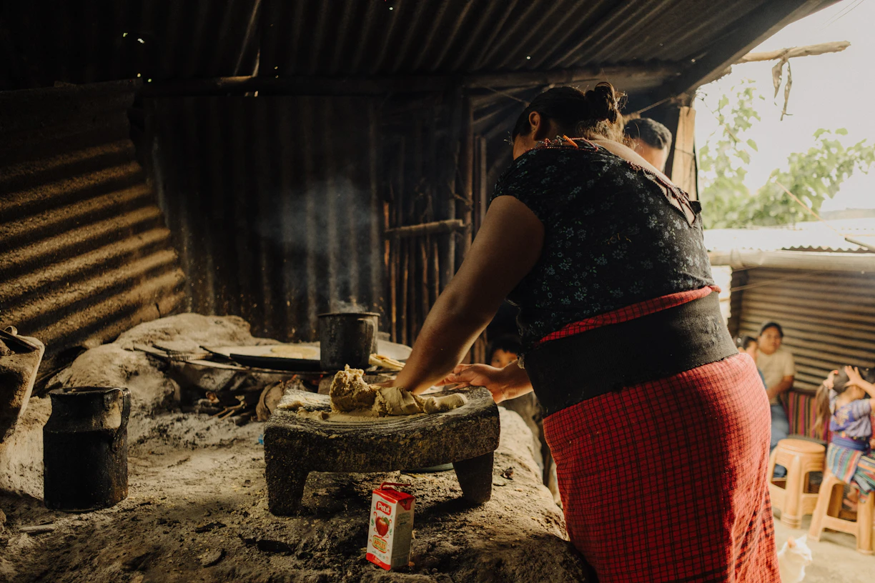 a woman cooking food on a stove in a hut
